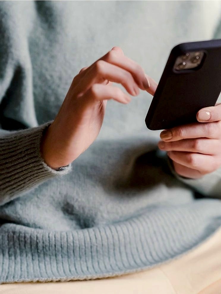 A woman looking at her phone in warm daylight, relaxed.